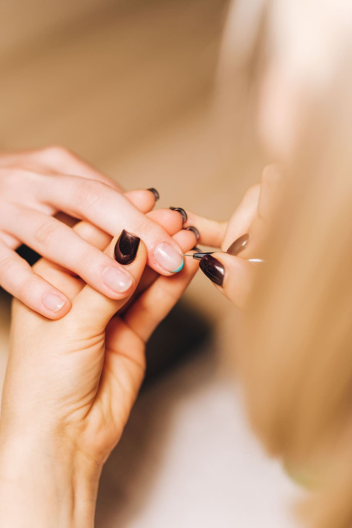 Manicurista pintando una uña con un pincel fino